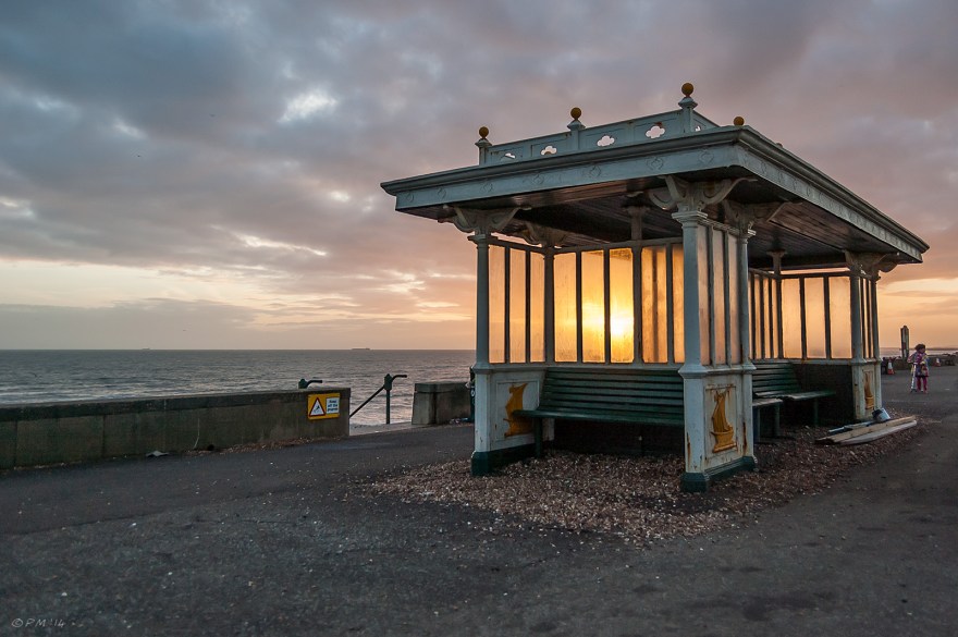 Sunset seen through bench shelter windows Hove Lawns sea front promenade, moody sky 16-2-14