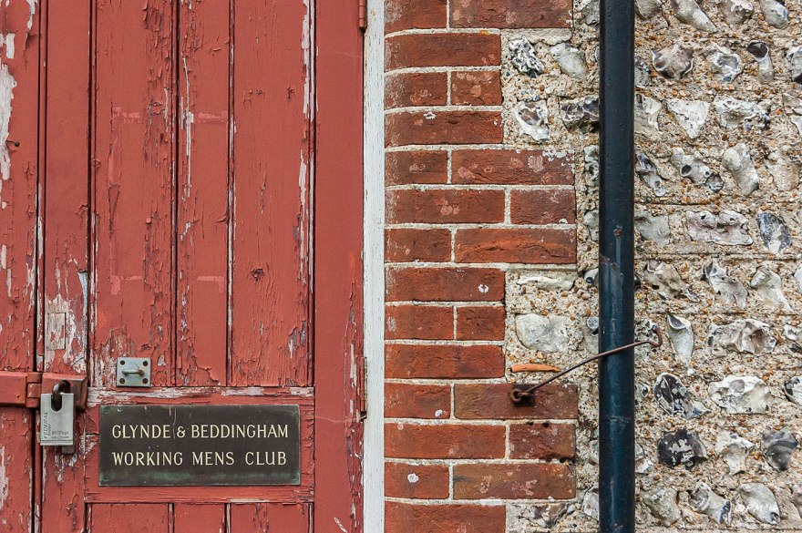 red door and knapped flint wall abstract with sign saying Glynde And Beddingham Working_Mens Club East Sussex 15-6-2014 eyeteeth.net
