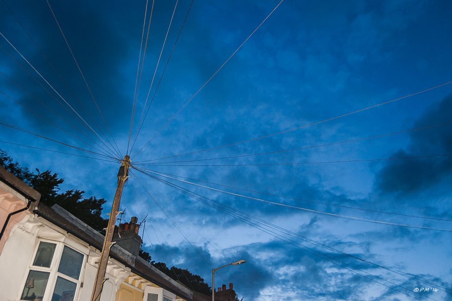 Telegraph wires radiating from pole against dark blue cloudy sky at dusk with illuminated houses  abstract Brighto Argyle Road 2014 eyeteeth.net