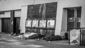 Homless people asleep in sleeping bags below film advertising in front of Odeon cinema. Monochrome landscape. Brighton East Sussex UK. P.Maton 2014 eyeteeth.net