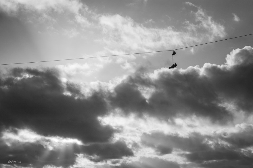 Shoes hanging by their laces on telegraph line with dramatic morning clouds in background. Monochrome landscape. © P.Maton 2014 eyeteeth.net