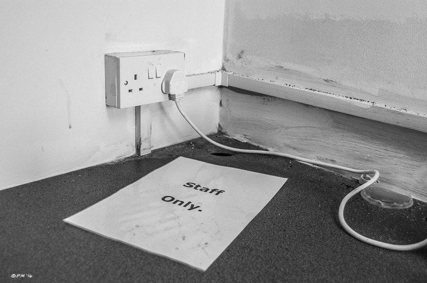 Staff Only notice lying on work top next to wall plug socket with cable extending out of shot. Abstract Monochrome Landscape. © P. Maton 2014 eyeteeth.net