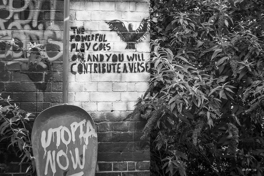 Political Graffiti on brick wall 'The powerful Play Goes on and you will contribute a verse' and 'Utopia Now' with Buddleia shrubs. Abstract Monochrome Landscape. © P.Maton 2014  eyeteeth.net