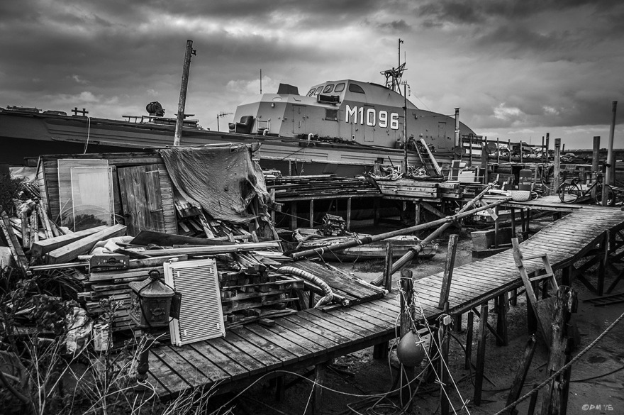 Minesweeper 'Fische' M1096 moored  next to Jetty with  piles of wood and clutter.  River Adur Shoreham Harbour UK. Monochrome Landscape. © P. Maton 2015 eyeteeth.net