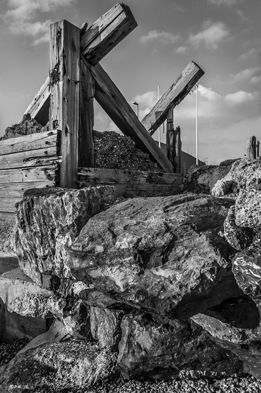 Wooden Sea defence on top of boulders with scattered clouds in sky. Shoreham Sussex UK. Monochrome Portrait. © P. Maton 2015 eyeteeth.net