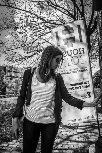 Woman touching wall by House 2015 sign with tree in background casting shadows towards camera. St Nicholas Church Brighton UK. Brighton House Festival, Brighton Festival. Monochrome Portrait. © P. Maton 2015 eyeteeth.net