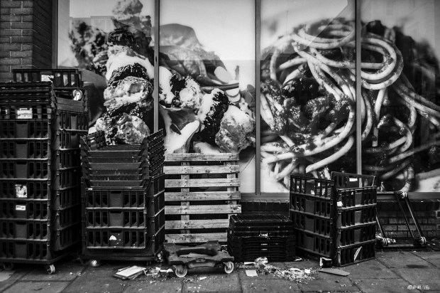 Food containers stacked on pavement sidewalk, in front of giant food photographs in shop window. Dyke Road Brighton UK. Monochrome Urban Landscape. © P. Maton 2015 eyeteeth.net