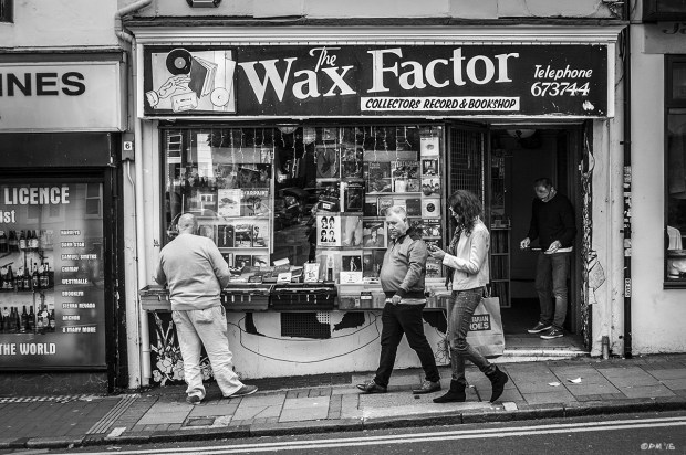 Wax Factor Record and Book store with Man browsing Trafalgar Street Brighton UK. Monochrome Landscape. © P. Maton 2015 eyeteeth.netstock on street as people walk by and shop keeper examining vinyl record in doorway. 
