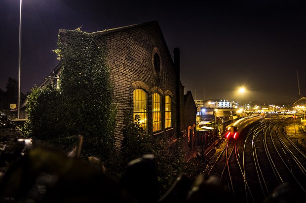 Victorian railway building at night with train passing and lights reflected in windows. Brighton Train Care Depot, Combined Engeneering Depot. Brighton Sussex UK. Urban Colour Landscape. © P. Maton eyeteeth.net