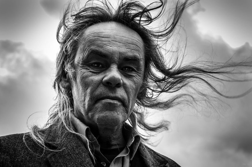 Man with rugged aged face and long hair blowing in wind. Black and white portrait. Oxfordshire, England UK. © P. Maton 26/12/15