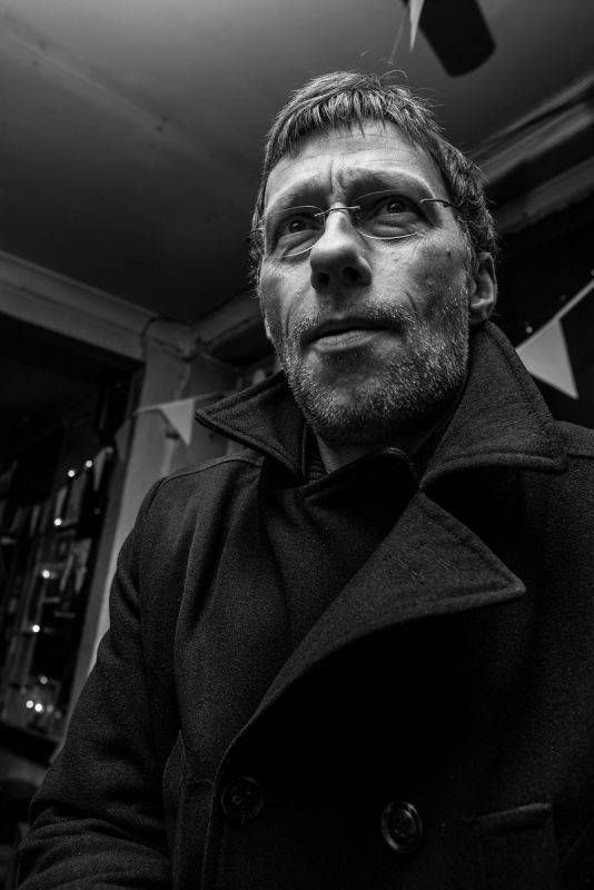 Man in wool overcoat with spectacles speaking in bar. Shakespeare's Head Pub Brighton UK. Black and white urban nightlife photography. © P. Maton 2017 eyeteeth.net