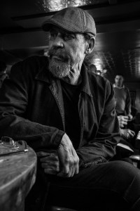 Bearded man wearing flat cap sitting at table in bar, Evening Star Pub Brighton UK. Black and white natural light documentary portrait. © P. Maton 2017 eyeteeth.net