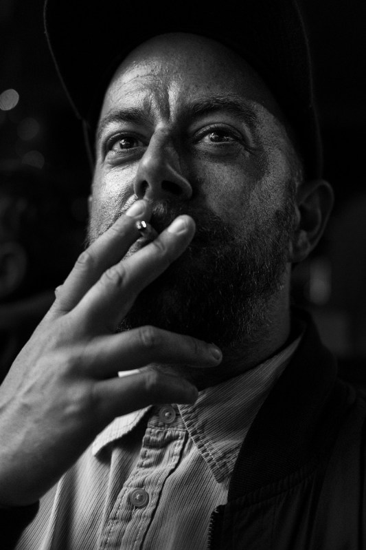 Man with beard and baseball cap raising cigarette to his lips black and white portrait face and hand Chatham Place Brighton UK © P. Maton 2017 eyeteeth.net