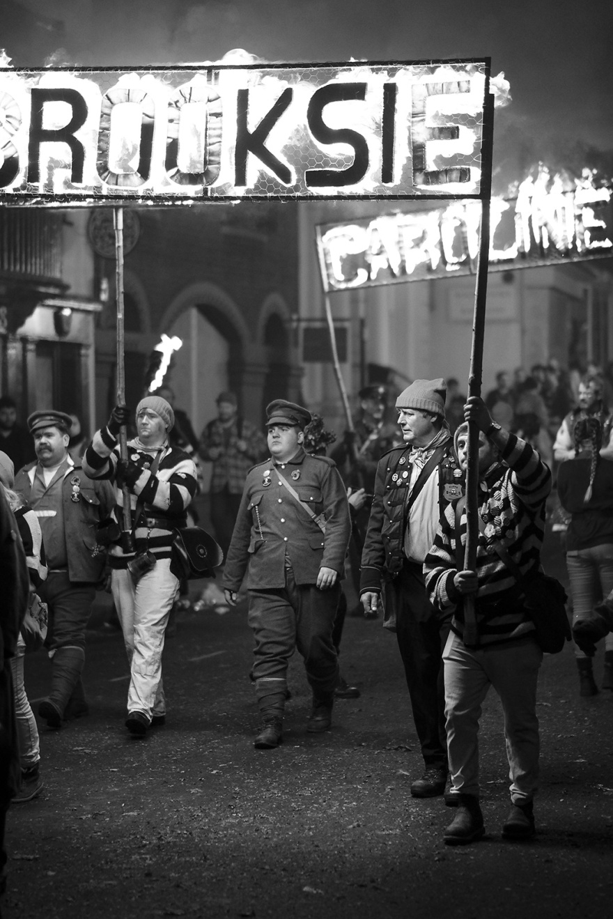 Male torch bearers in costume with burning standards Lewes bonfire night High Street Lewes East Sussex UK, black and white night photography Britain © P. Maton 2018 eyeteeth.net