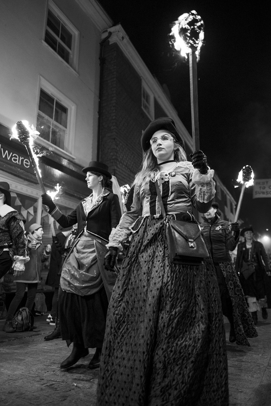 Female torch bearers in period costume with burning torches Lewes bonfire night Cliffe High Street Lewes East Sussex UK, black and white night photography Britain © P. Maton 2018 eyeteeth.net